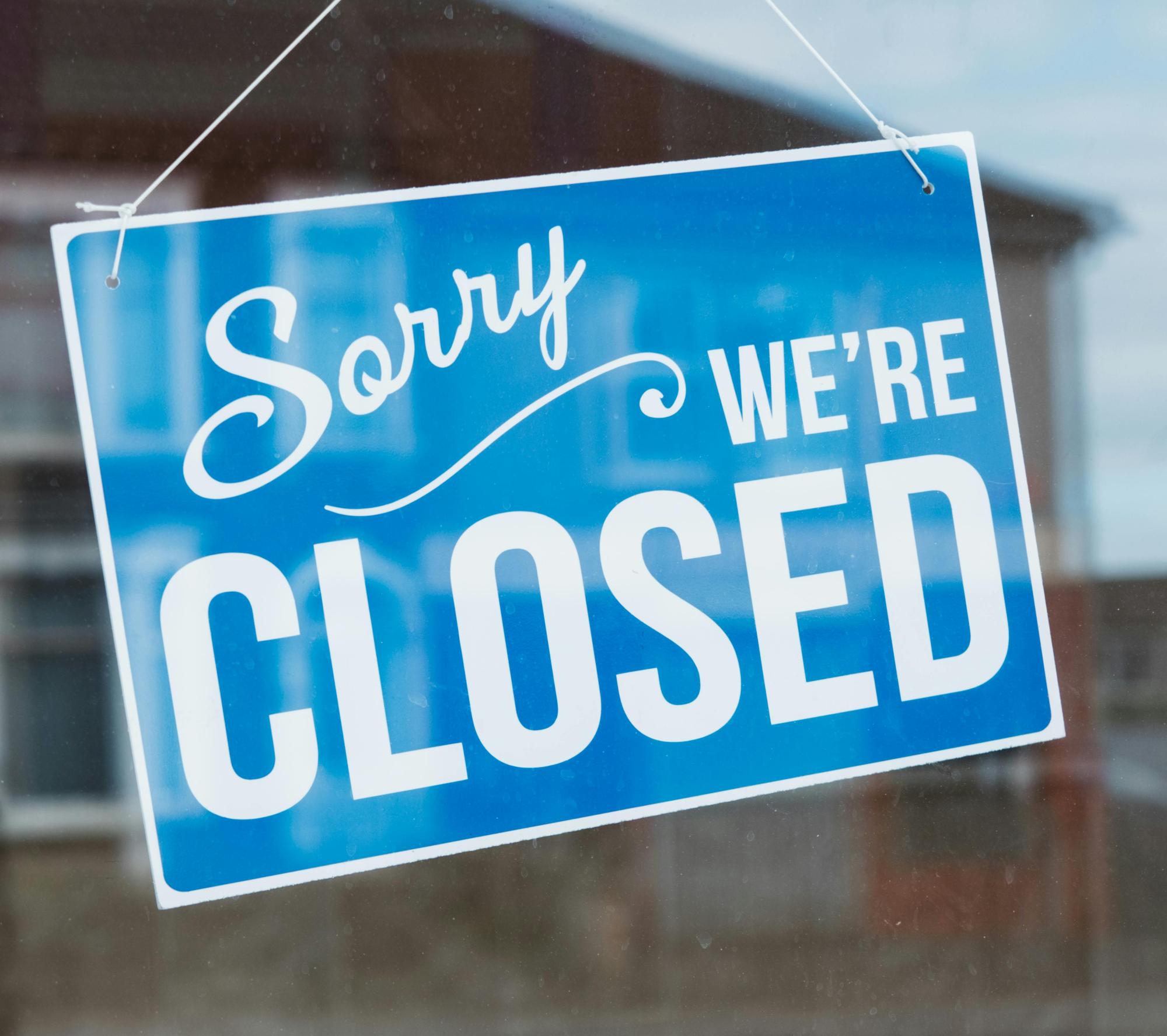Light blue sorry we're closed sign hanging on window