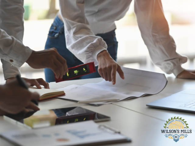 People looking at building plans on a table with a level tool